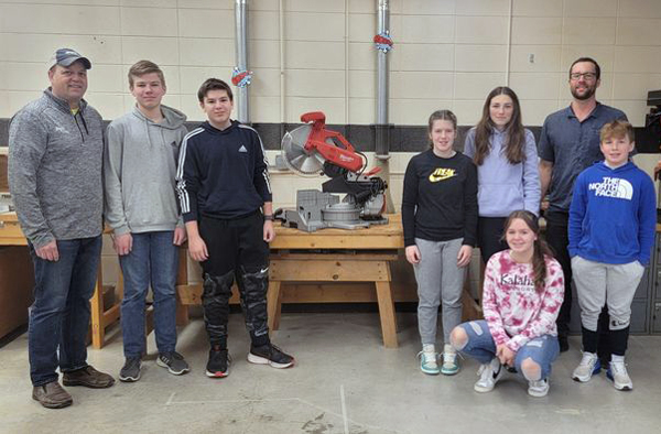 donor, teacher, and students with saw