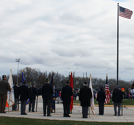 veterans and students around flagpole