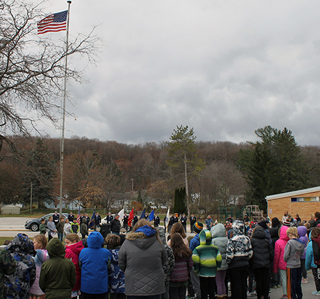 veterans and students around flagpole