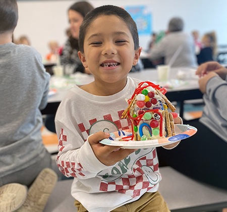 student holding gingerbread house