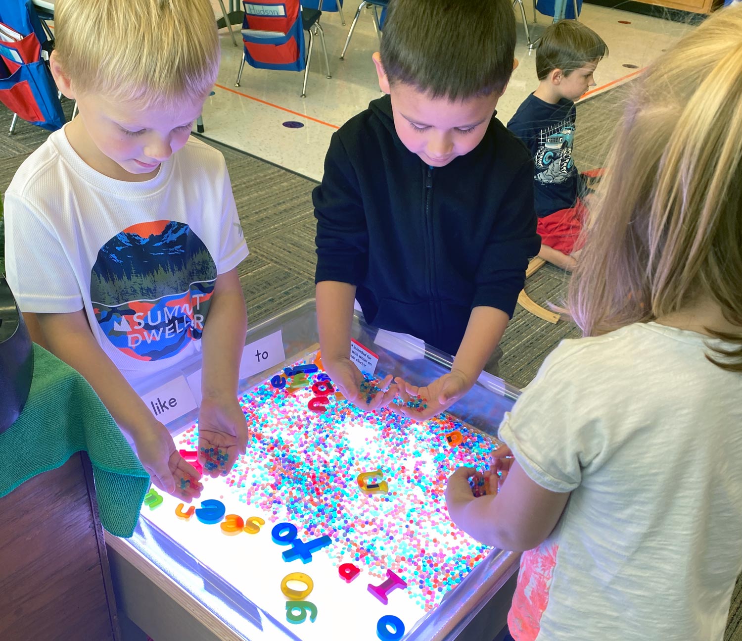 Parkview kindergartners working with letter shapes at the light table