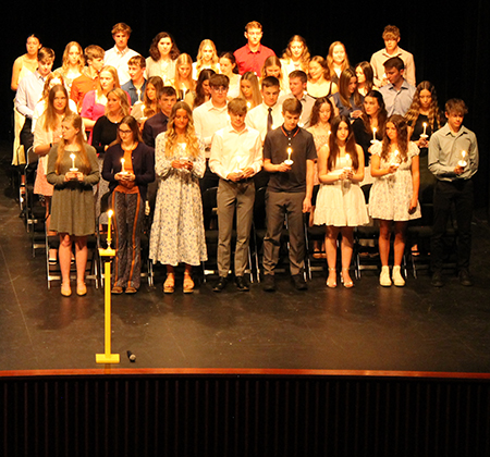 students on stage with candles