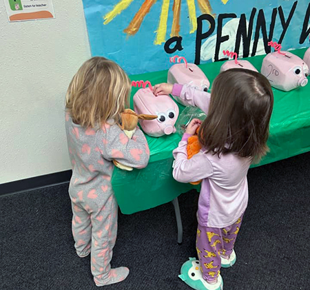 Parkview students in pajamas putting money in piggy bank