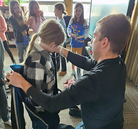 racecar driver helping student into outfit