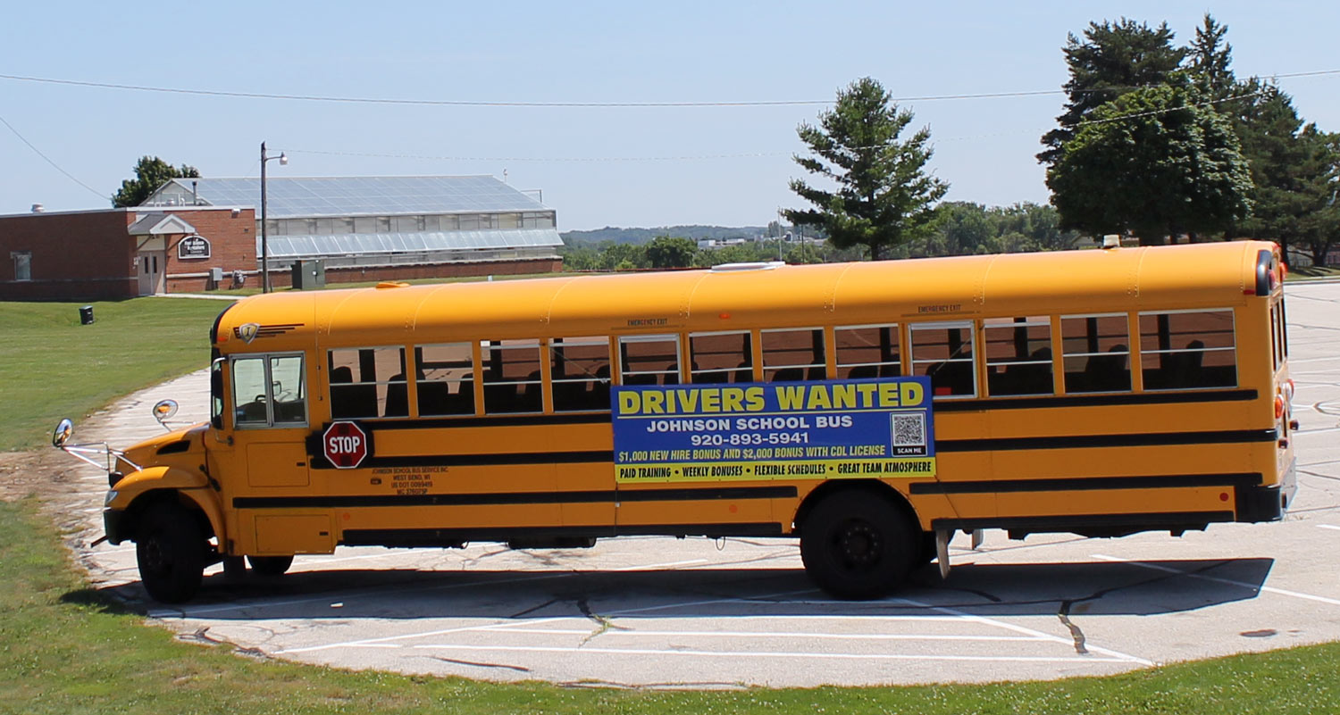 help-wanted banner on school bus outside PHS