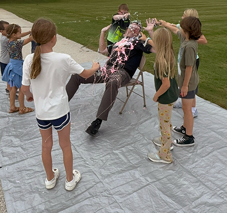 students spraying principal with silly string