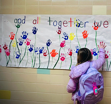 Parkview student touching banner of hand-print flowers