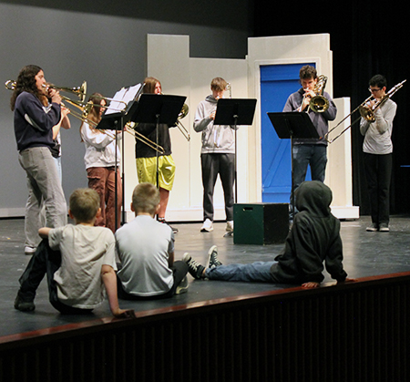 PHS trombonists playing on stage for young students