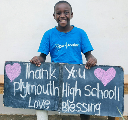 child holding sign with words Thank you Plymouth High School, Love Blessing
