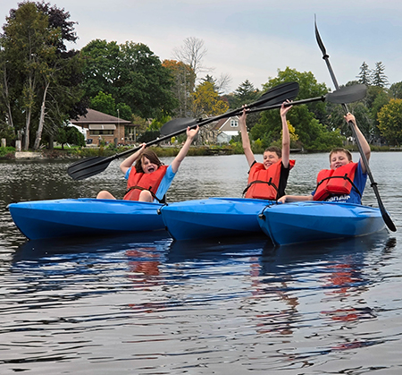 three students in kayaks